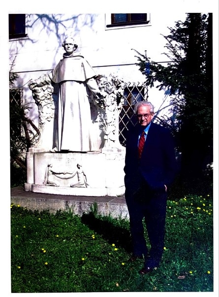 Dr. Marshall Nirenberg standing before a statue of Gregor Mendel