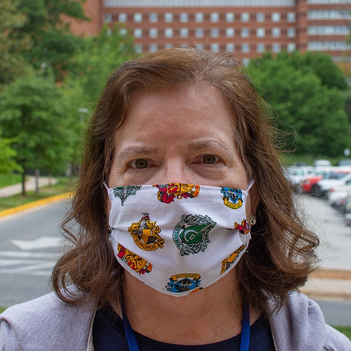 An NIH Employee wearing a Mask to prevent COVID-19 Spread, standing in front of the NIH Clinical Center on Campus