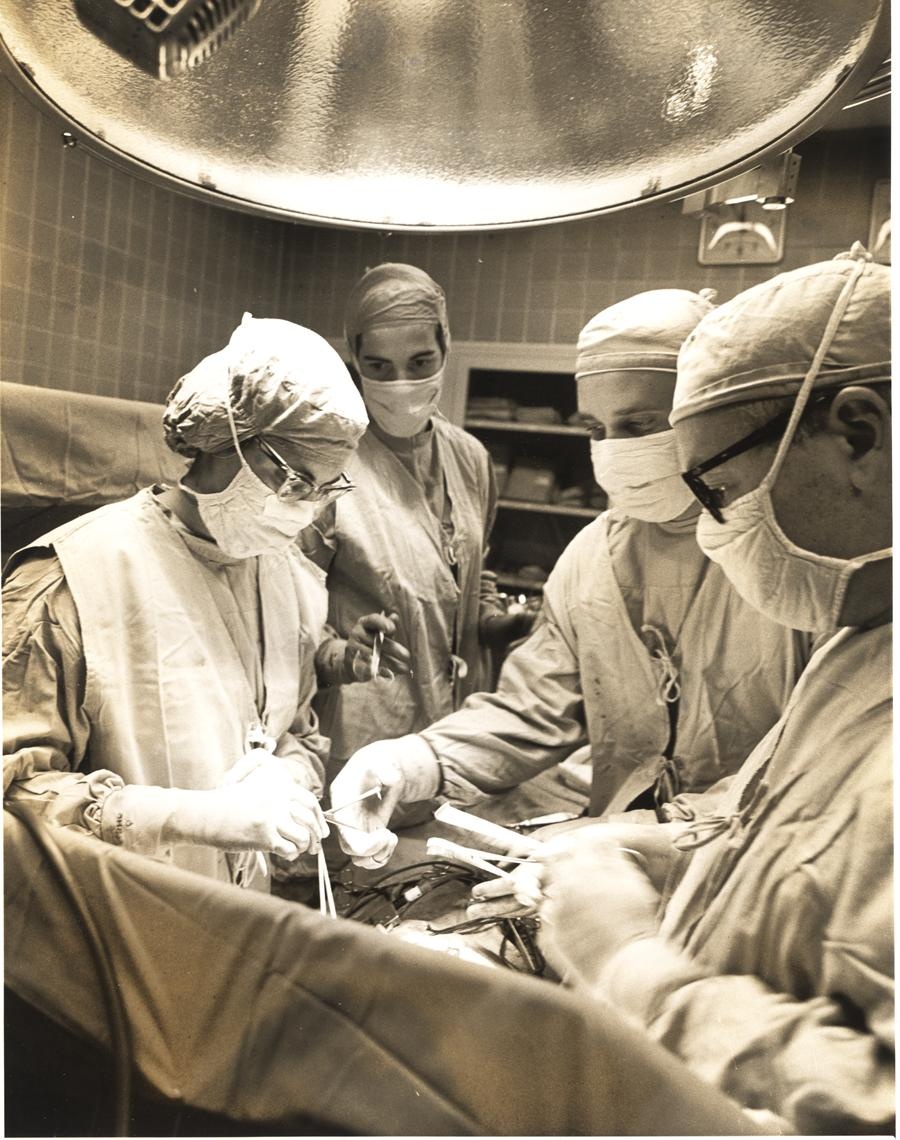 black and white photo of surgeons who are conducting open heart surgery on a patient