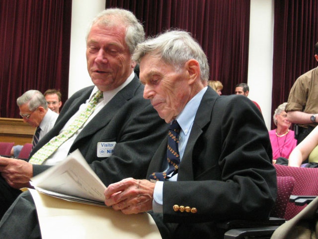 Two men reading a paper while attending a conference