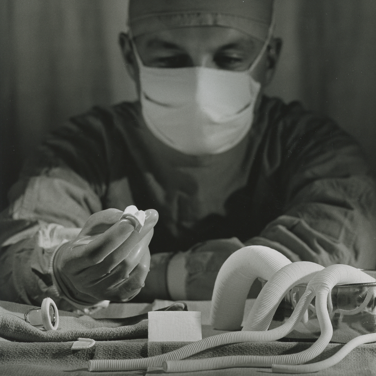 a surgeon wearing a mask inspects various heart valves