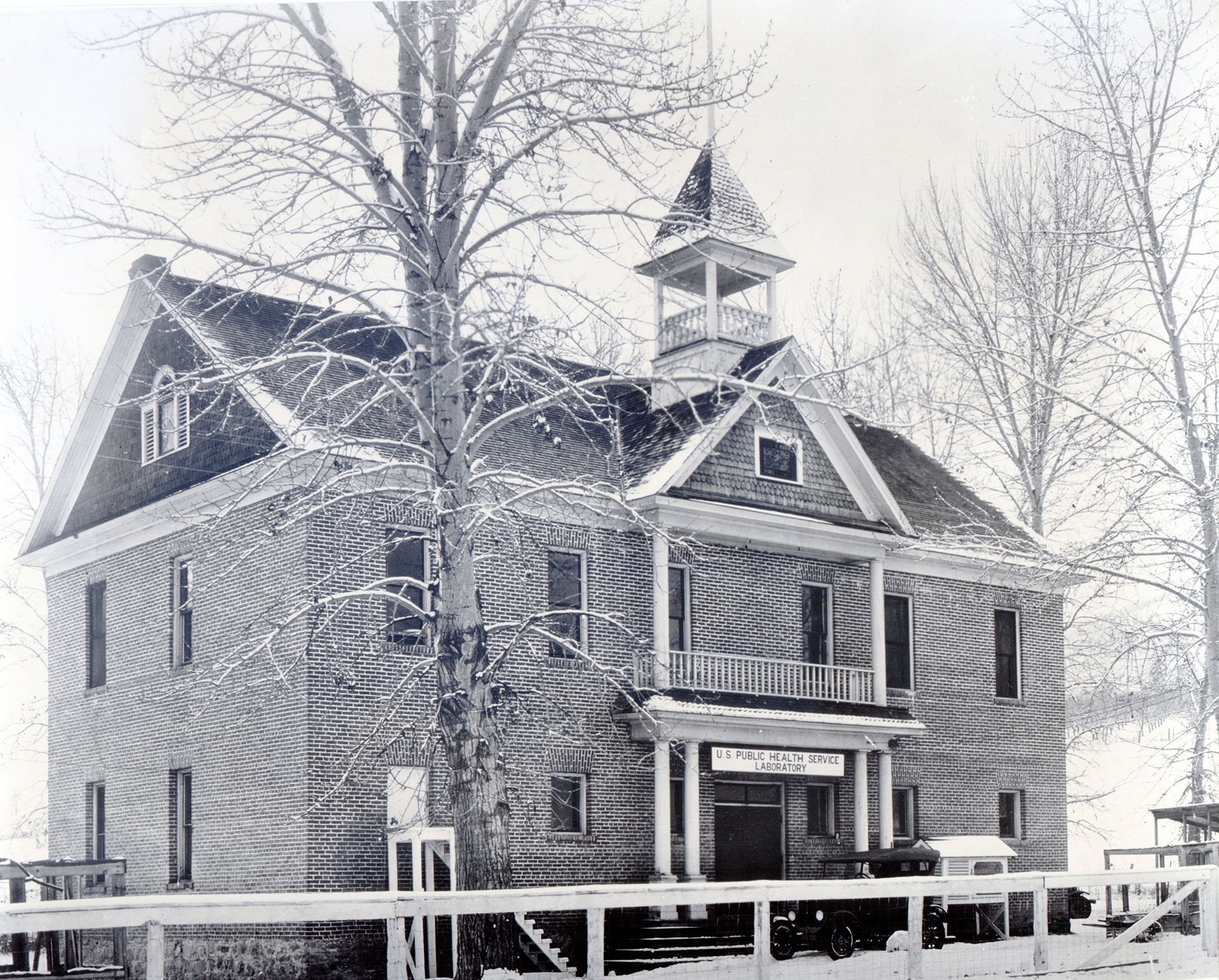 The Canyon Creek Schoolhouse Laboratory is a two story brick building with attic. A sign hangs from the door saying it's the U.S. Public Health Service Laboratory.