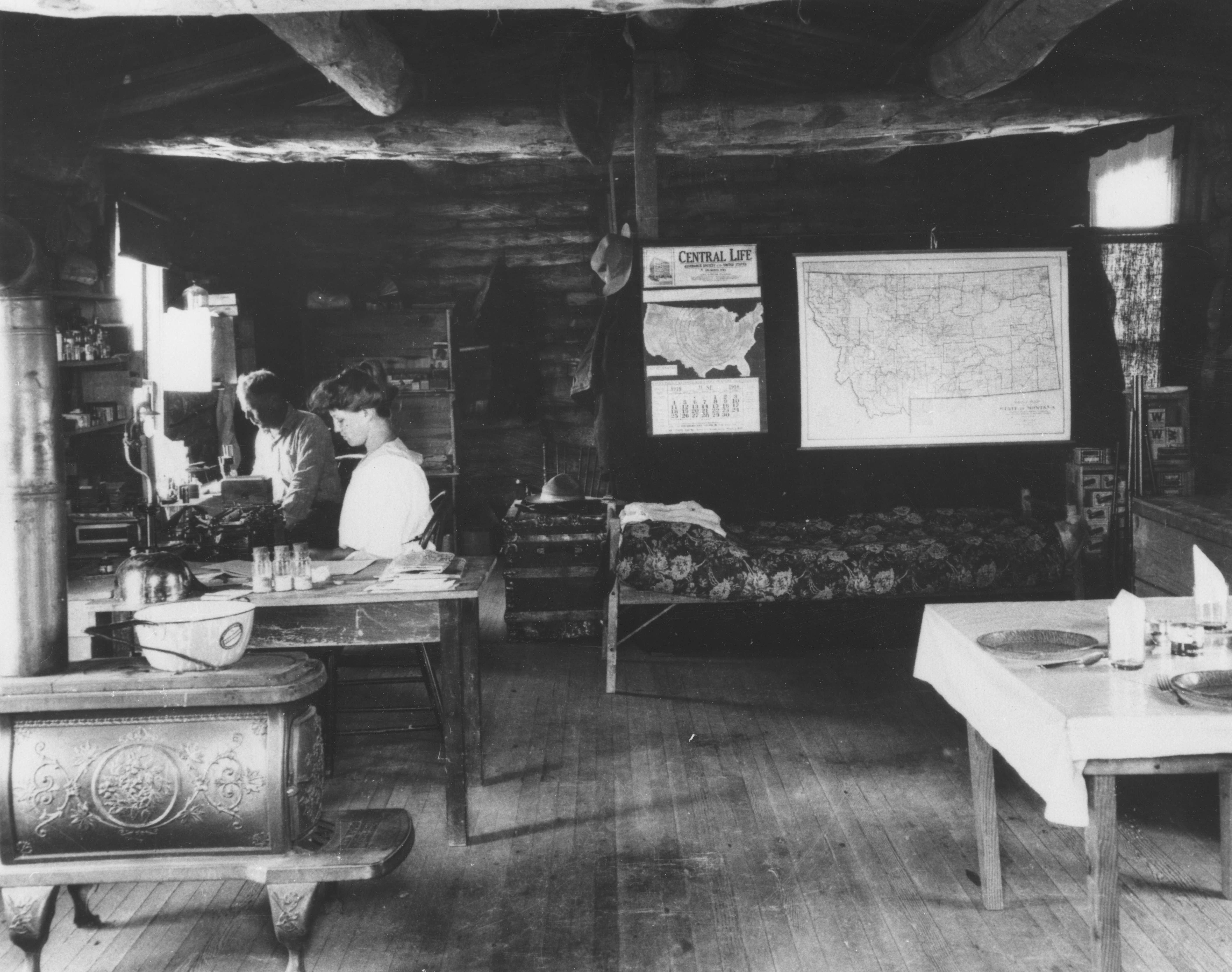  Dr. Ralph Parker in a log cabin in Montana. A woodstove is visible and the cabin is furnished with rustic decor.