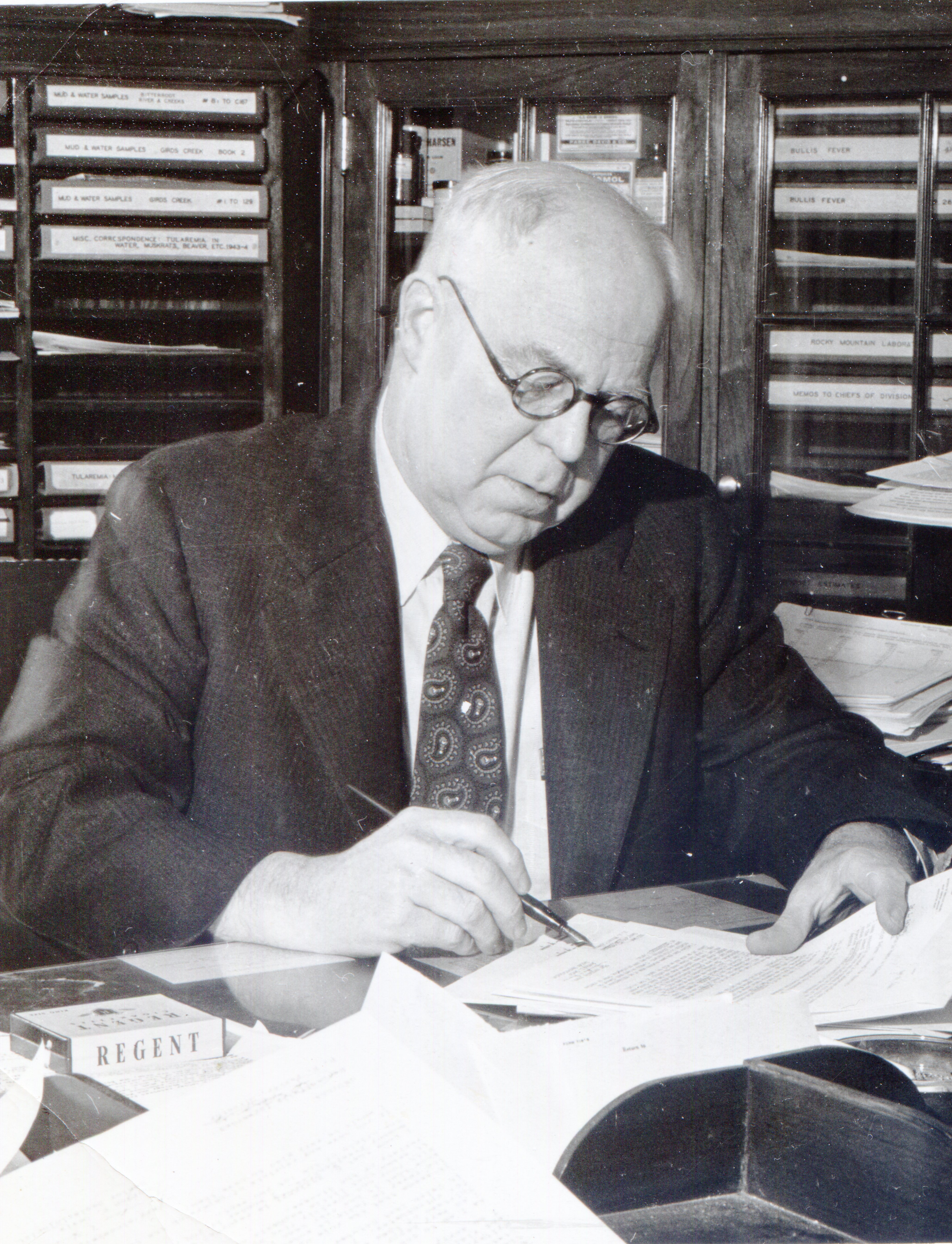 Ralph Parker sits at his desk in a nice suit, editing an article with a pen