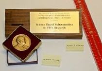 a photo of the FDA Commissioner's Special Citation Award which is a gold coin with a wooden stand for it