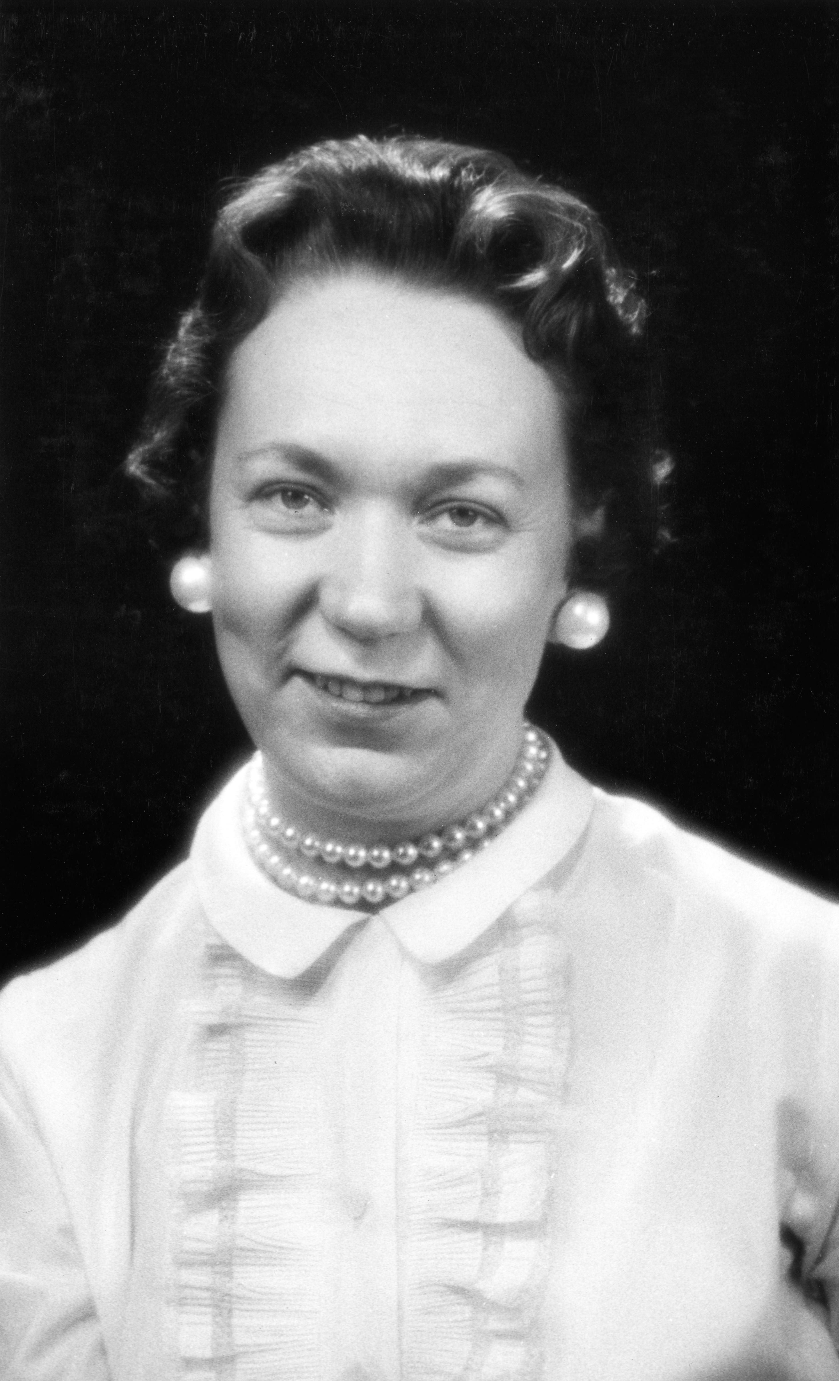 Professional photograph of Madge Crouch wearing a light shirt with a dark background