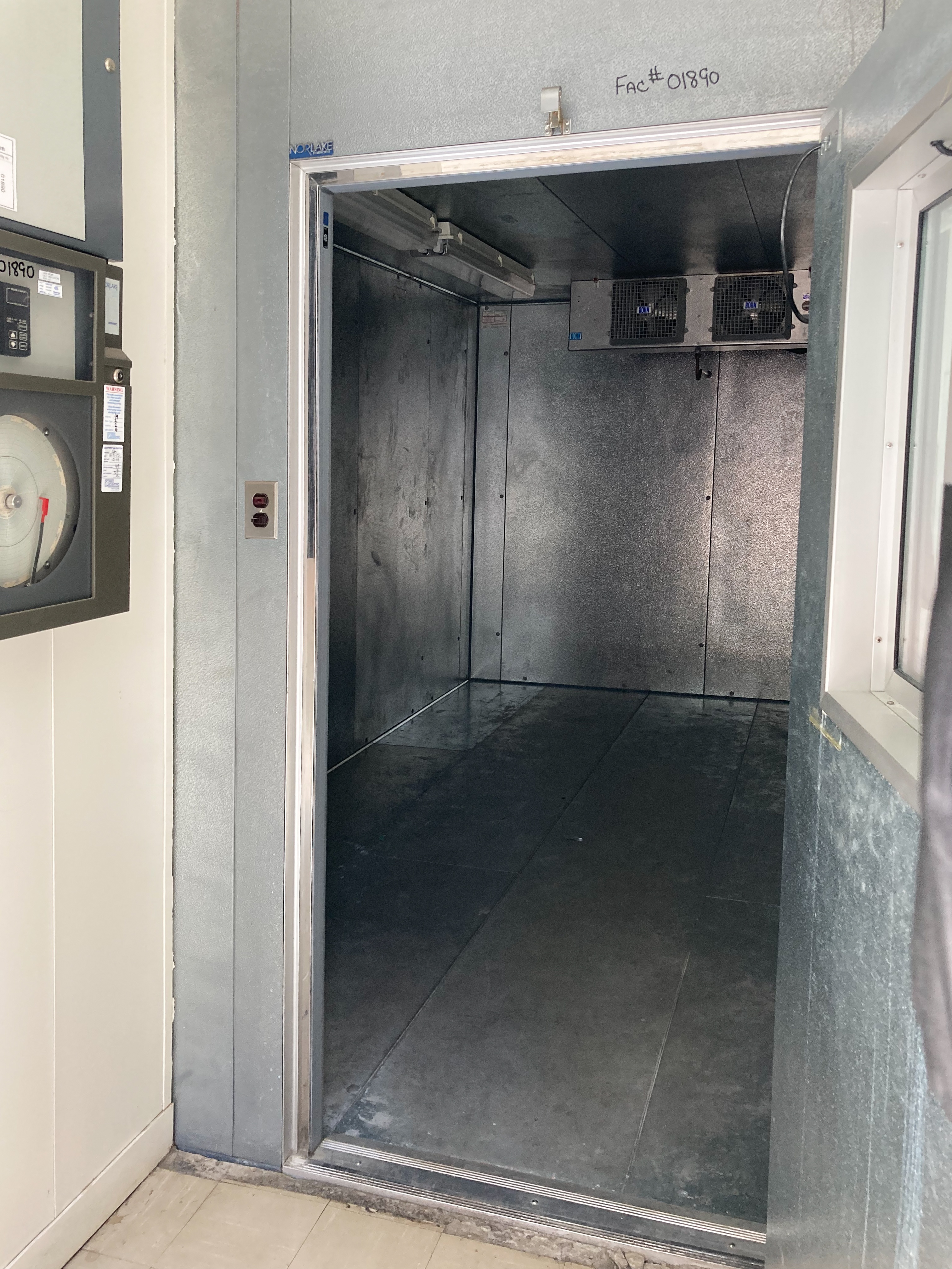 peering into the refrigerated room, the temperature controls and monitoring device can be seen to the left outside the room.