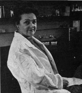 Dr. Bernice Eddy is seated in a chair in her laboratory wearing a white lab coat.