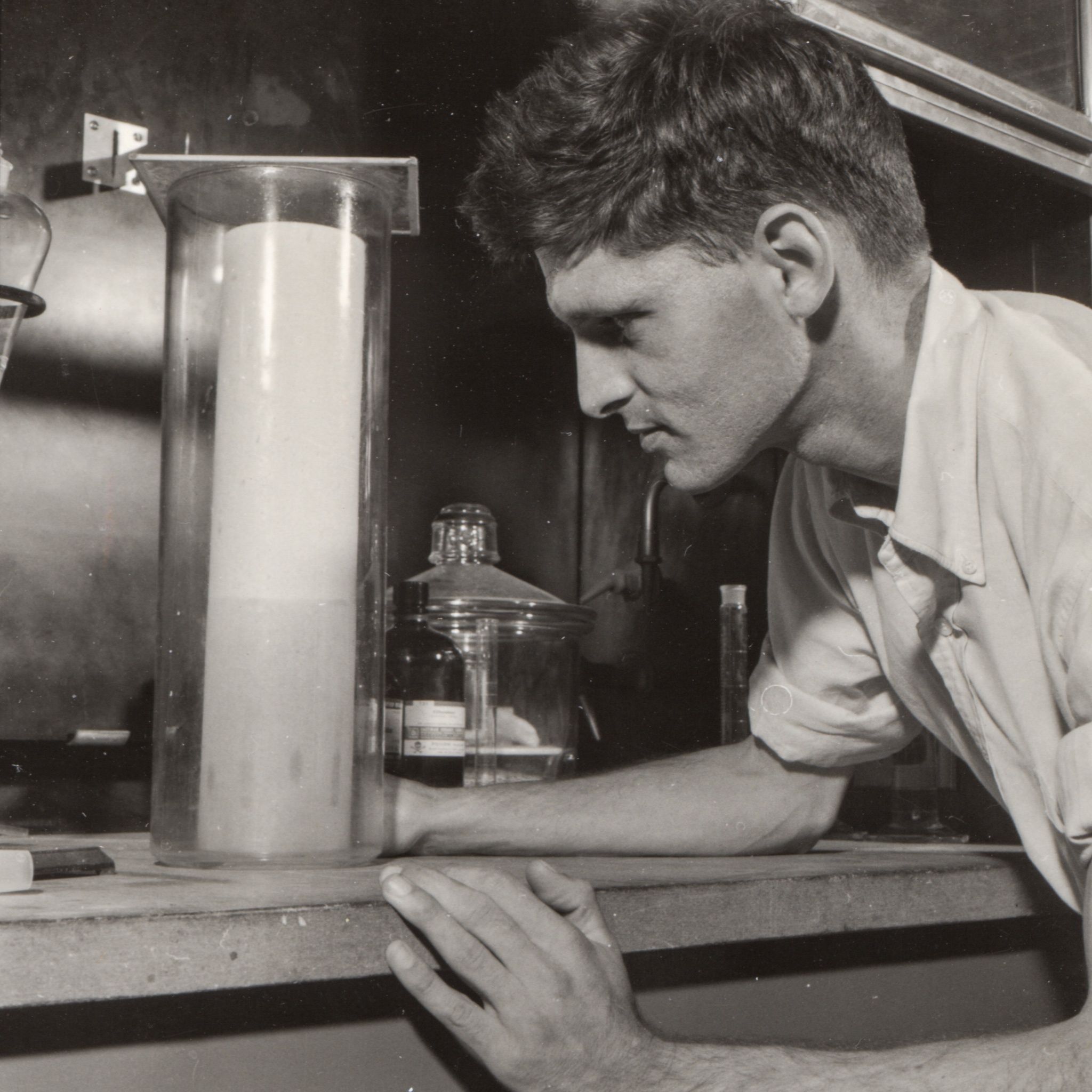 a black and white photo from 1963 of a man doing paper chromatography in a fume hood