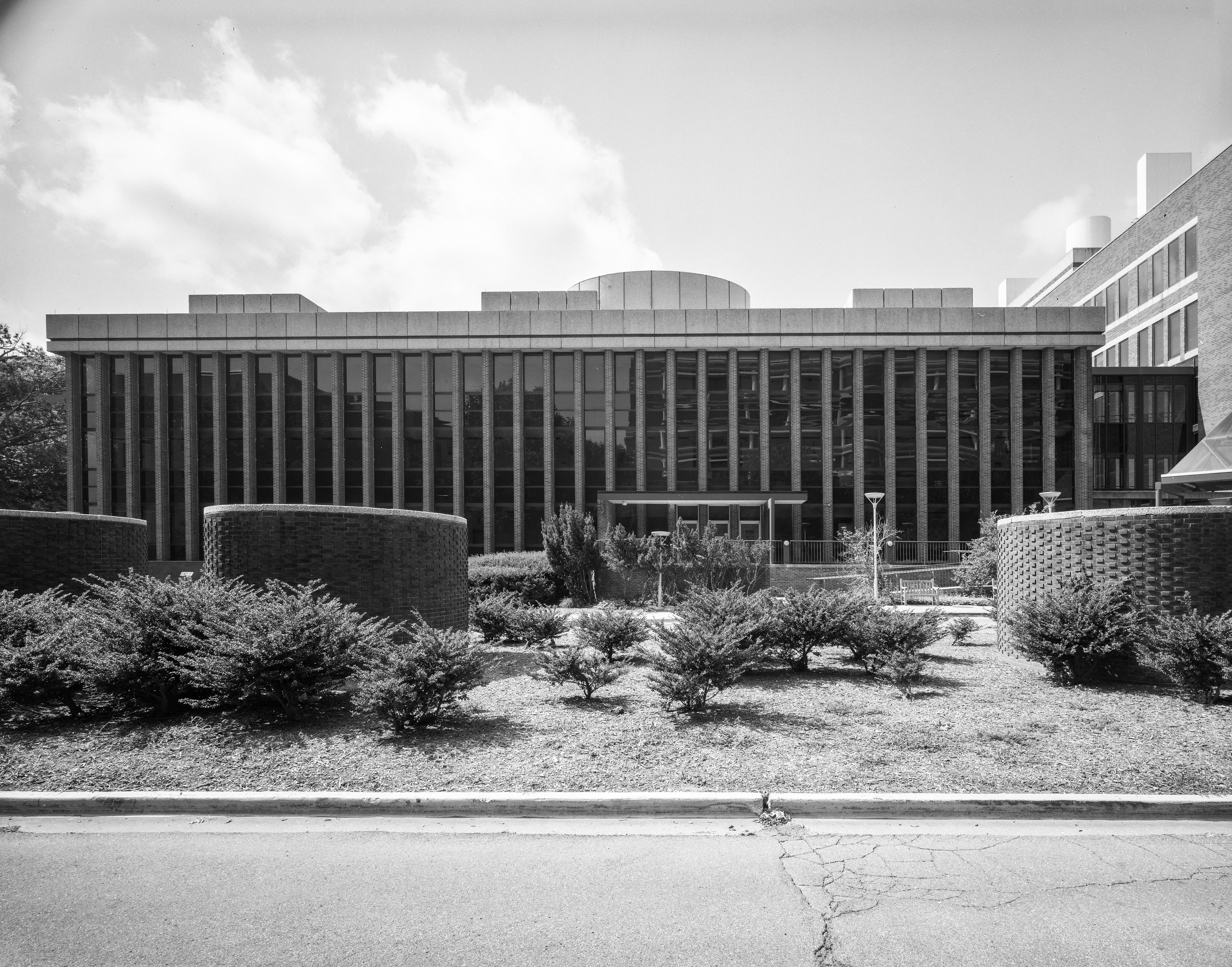 a black and white photo of the front of Building 29 with round air intake towers in front in a grassy median