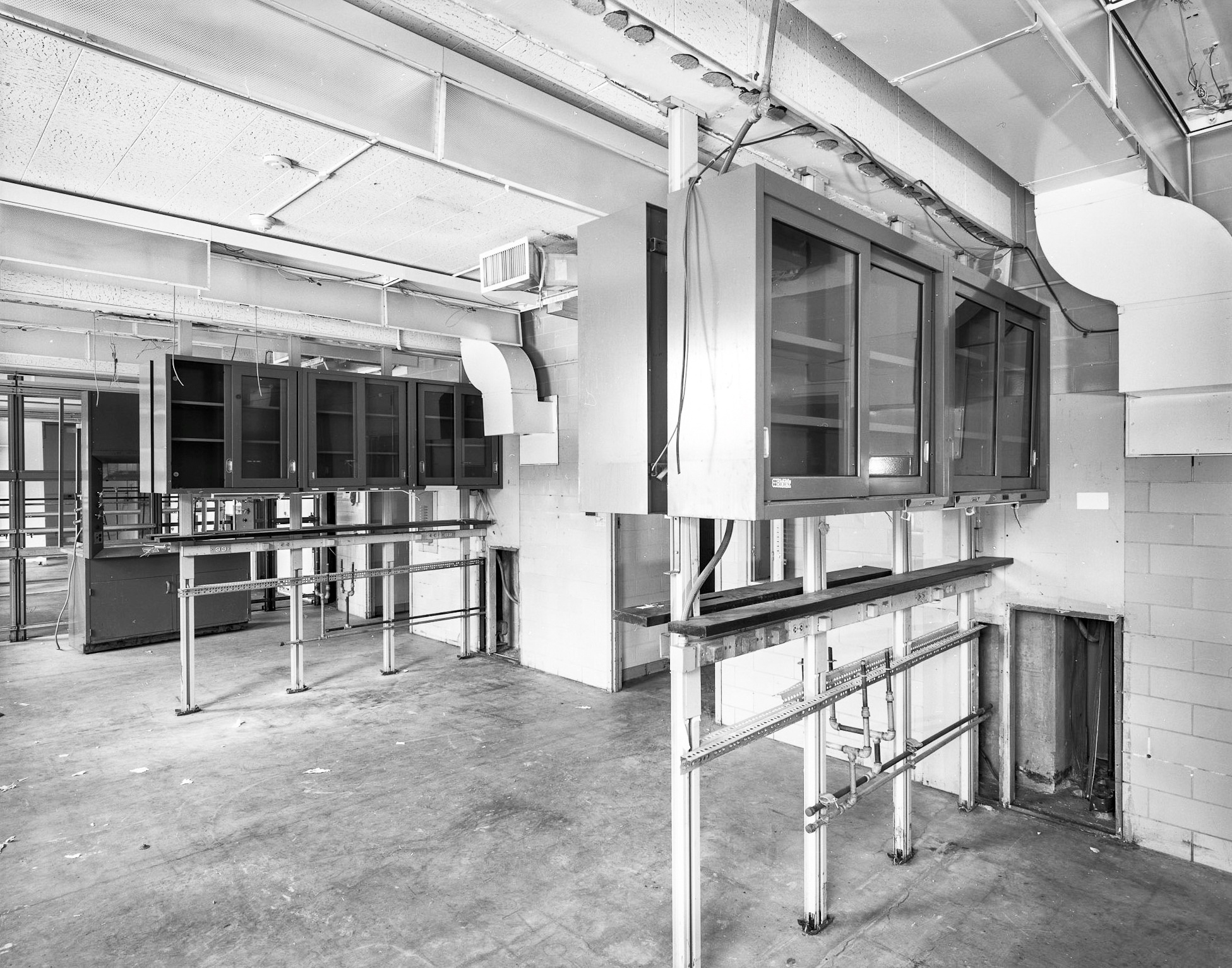 Interior black and white HABS photograph of a lab with the shelving and cupboards in place taken from the corner of the room