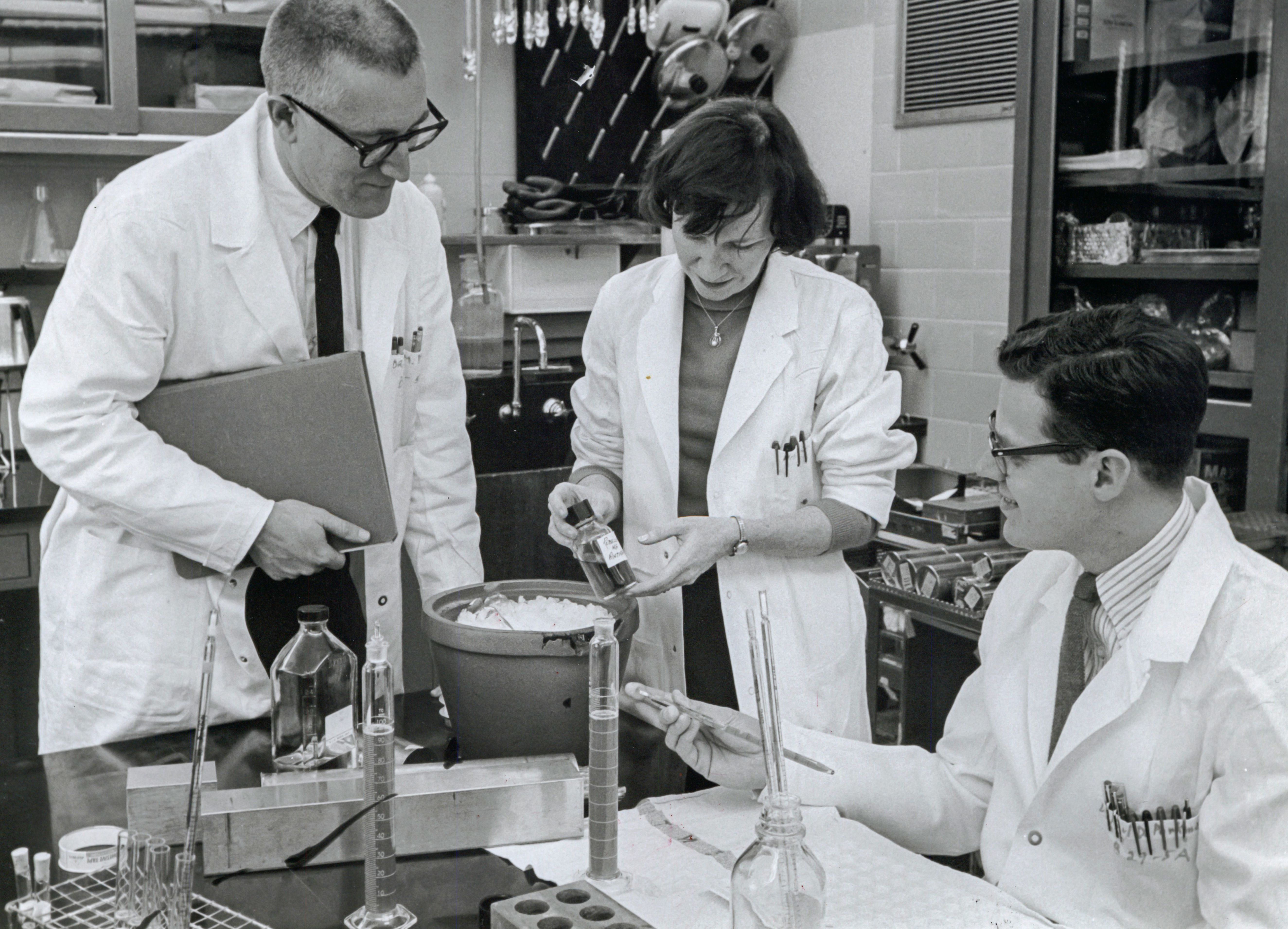 a photo of two men and one woman, Hope Hopps, in a lab, wearing white lab coats