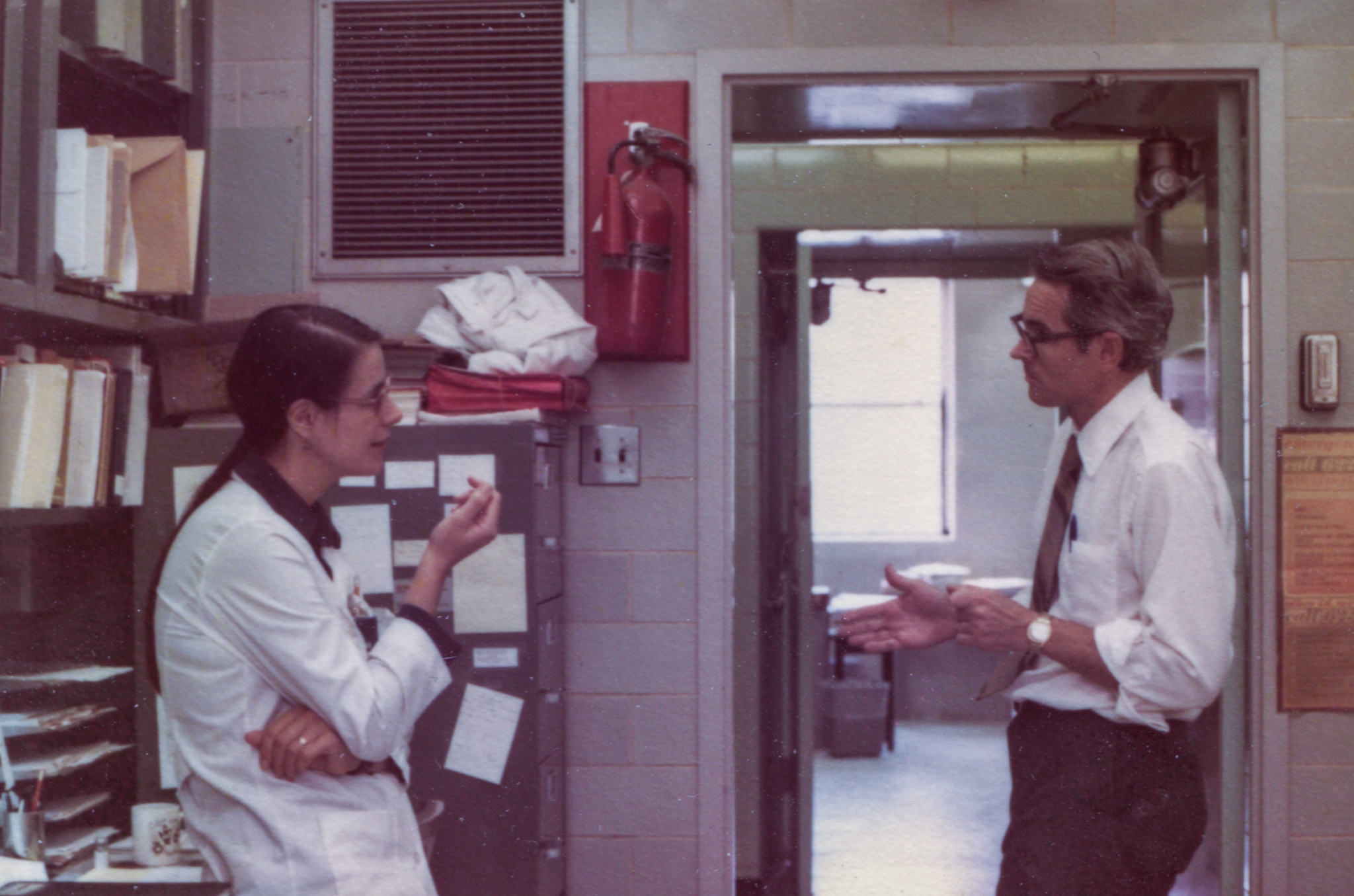 a color photo of a man and a woman in an office in Building 29 in 1973 deep in discussion