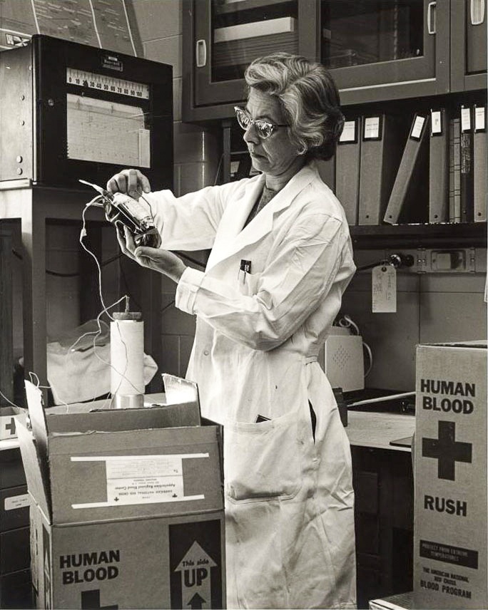 Dr. Sarah Stewart in the lab with a box of human blood. wearing white lab coat