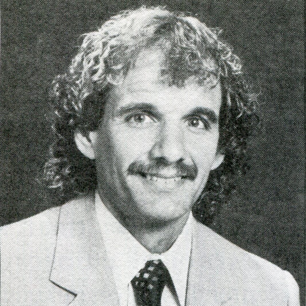a photo of a man with curly hair wearing a suit and tie