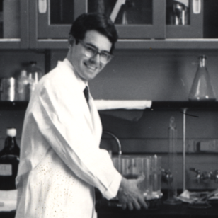 photo of Dr. Finlayson carrying a rack of test tubes in a laboratory