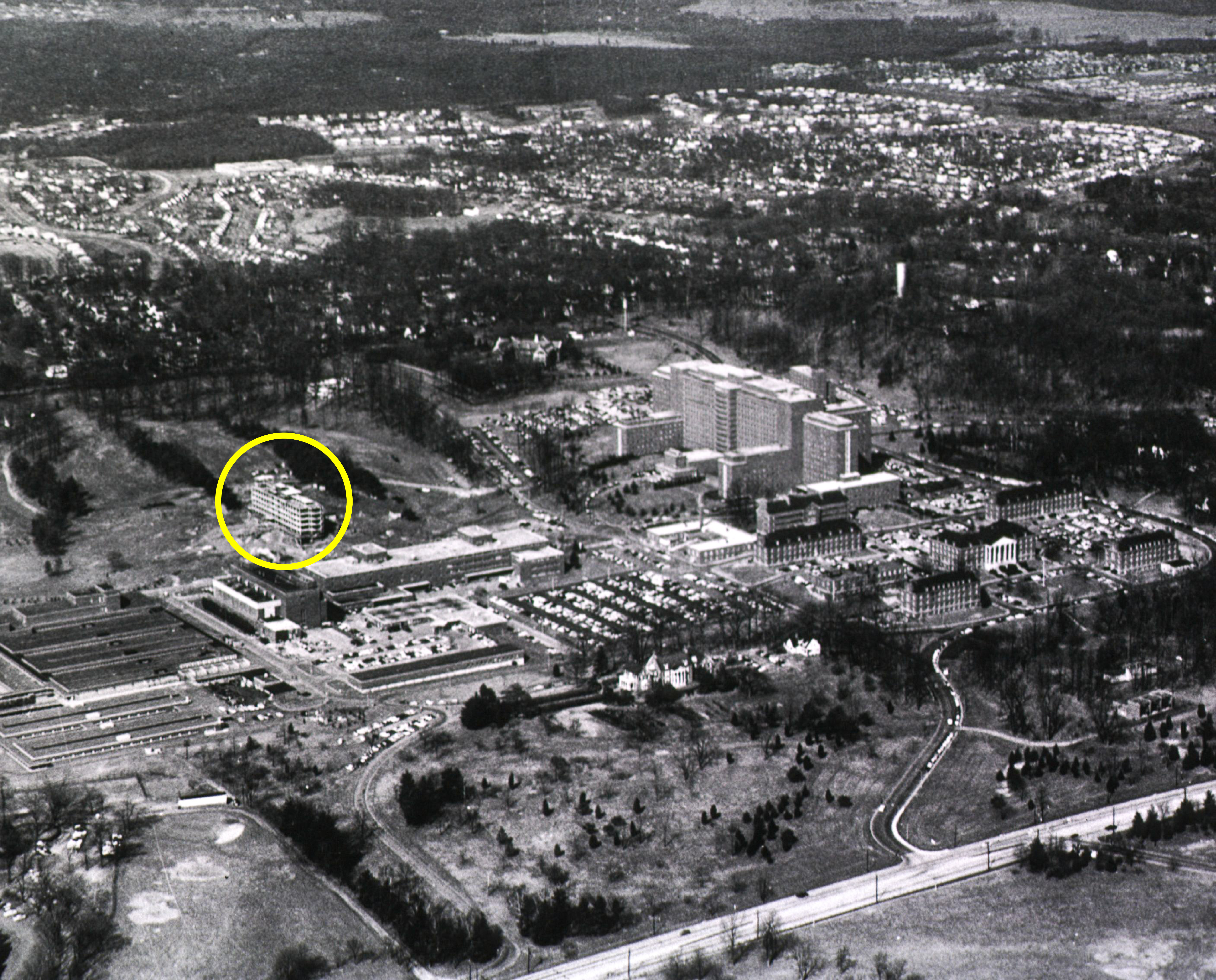 ca. 1960 black and white aerial image of NIH Bethesda campus with Building 29 under construction cirlced