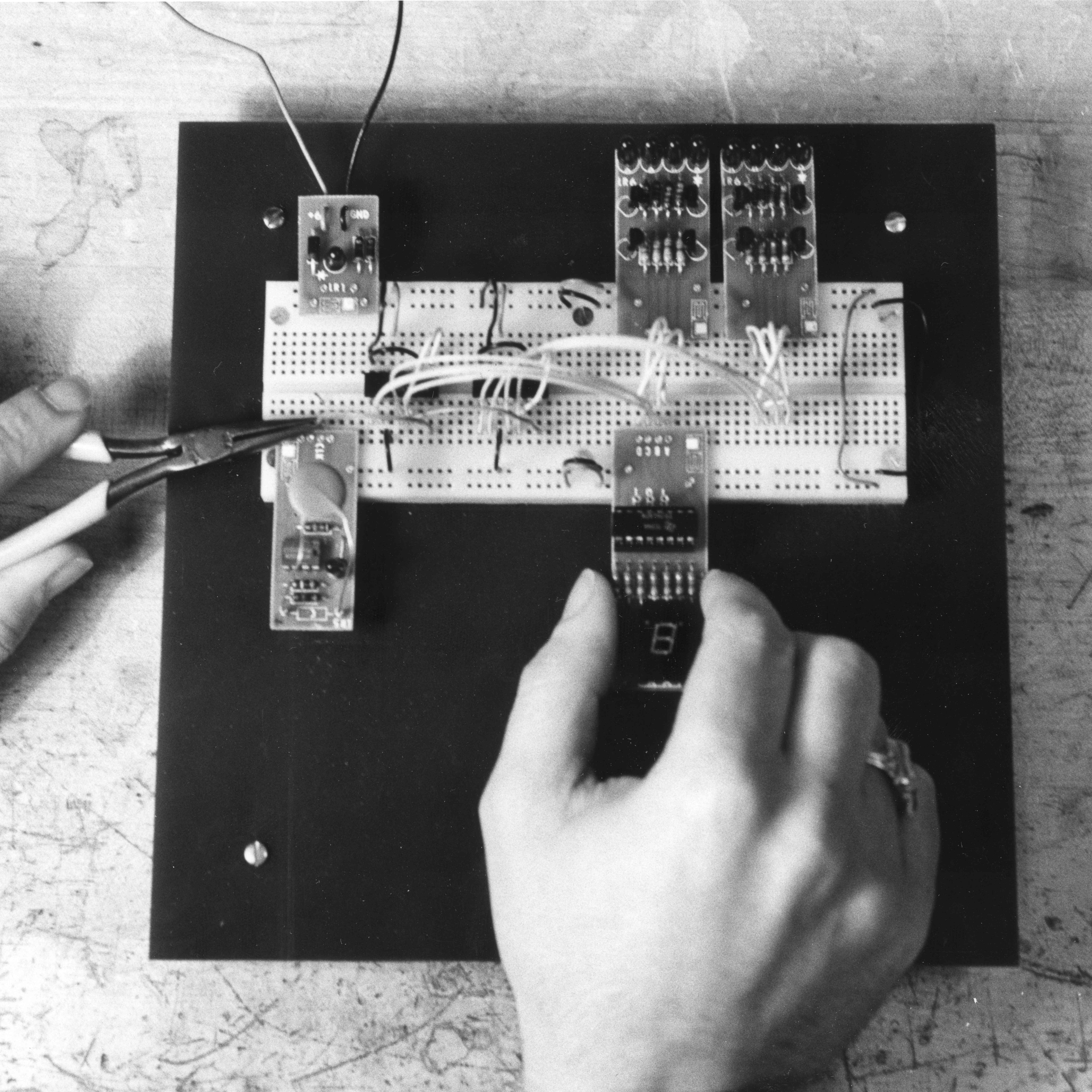 hands can be seen assembling circuits on a breadboard