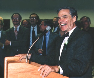 Martin Rodbell in a suit, seated and smiling or laughing