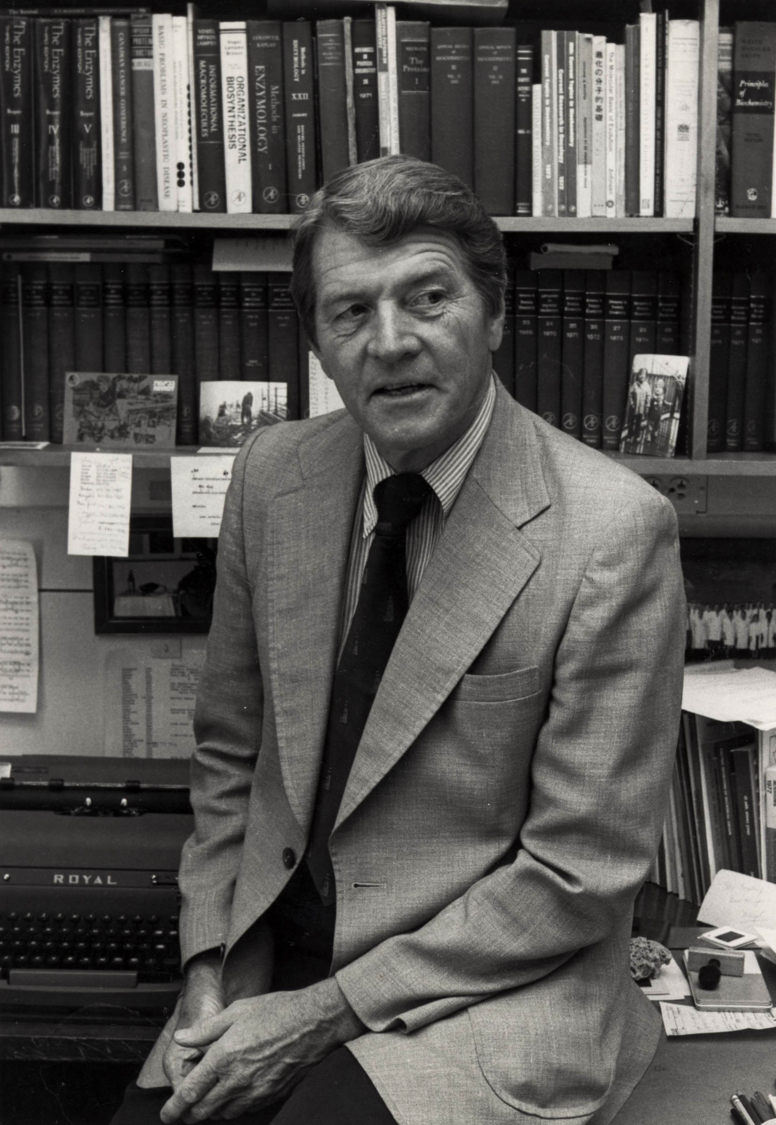 Anfinsen seated in front of bookshelves and a typewriter