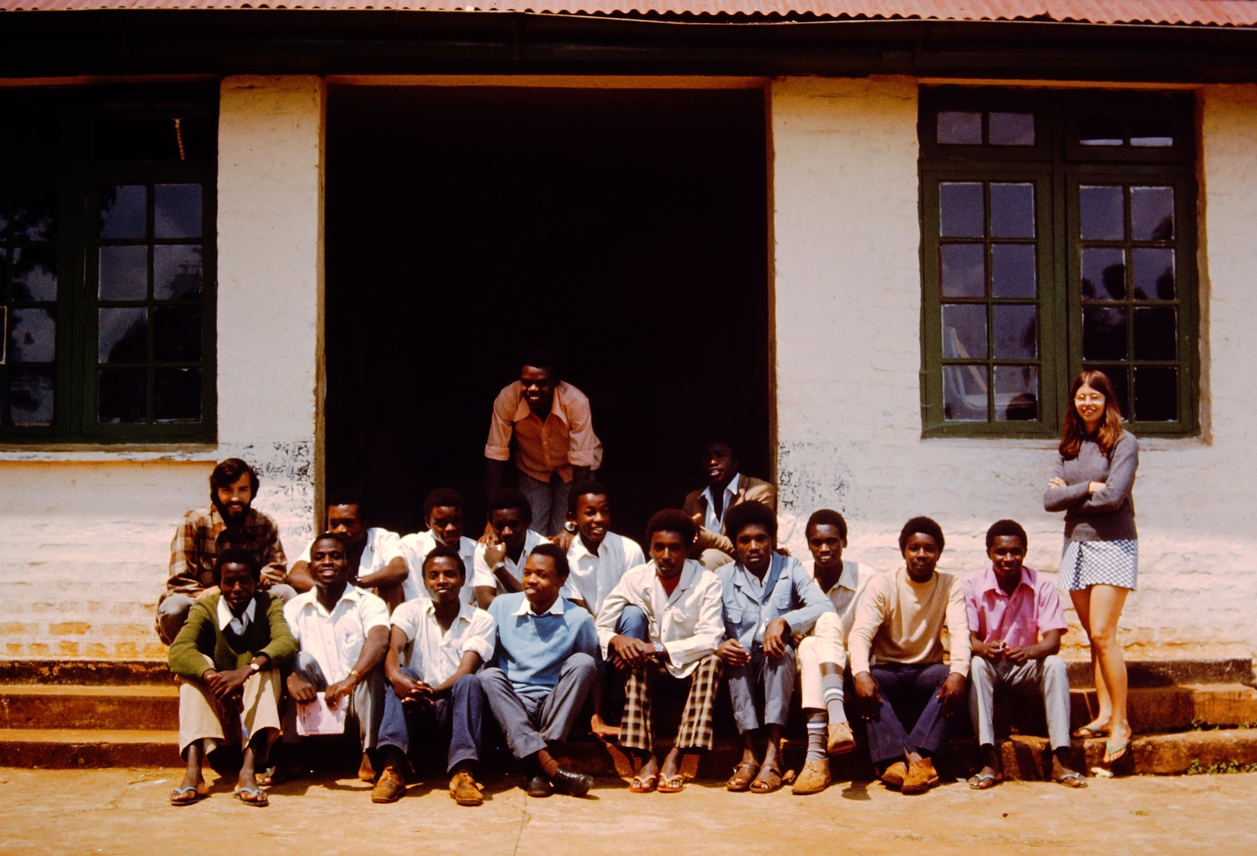 Three rows of young African men pose on the steps of a school.